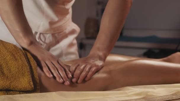 Feet massage of beautiful girl. Close-up of leg massage treatment in spa salon. Evening light. Relaxing body procedure. Therapist applying pressure on female leg. 4k, UHD - Metraje, vídeo
