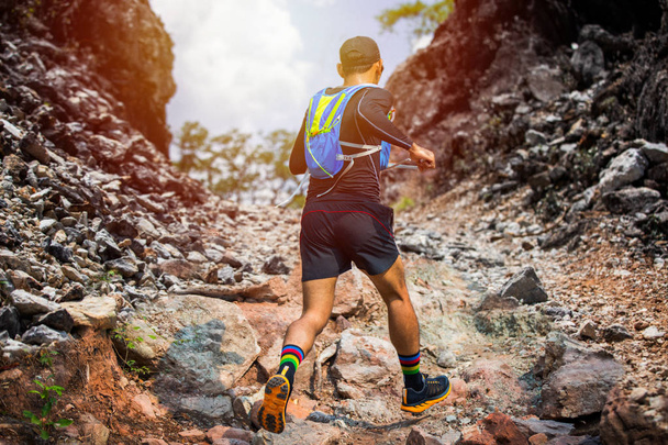 A man Runner of Trail and athlete's feet wearing sports shoes for trail running in the forest - Photo, Image