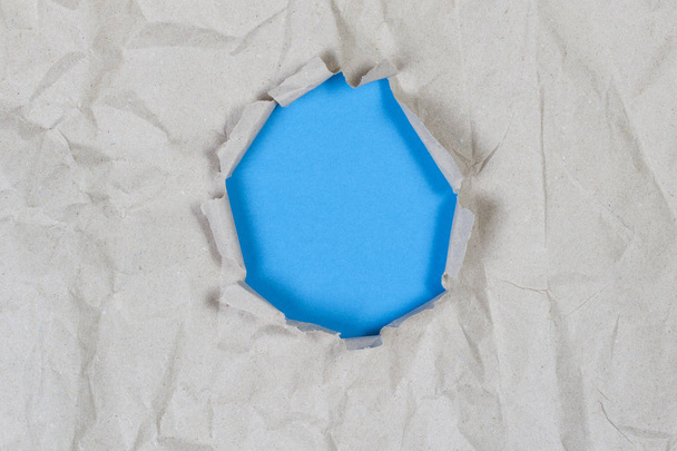Agujero en papel viejo arrugado con fondo azul claro en el interior
 - Foto, imagen