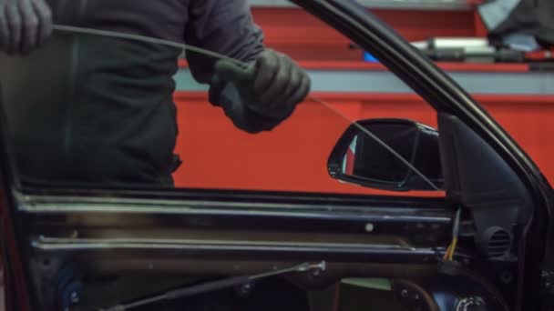 Un meccanico sta rimettendo un finestrino nella portiera dell'auto. Questo si svolge presso un servizio di auto
. - Filmati, video