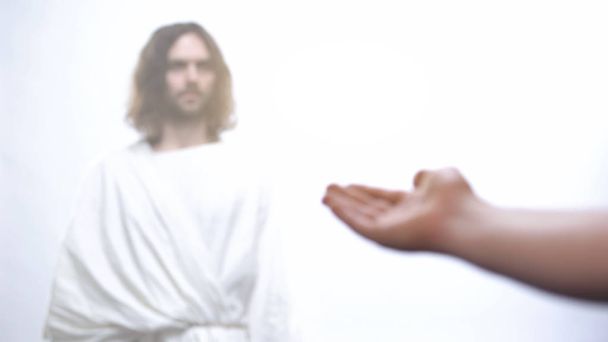 Hand of poor man praying to God, asking for wealth, Jesus standing in light - Foto, Imagen