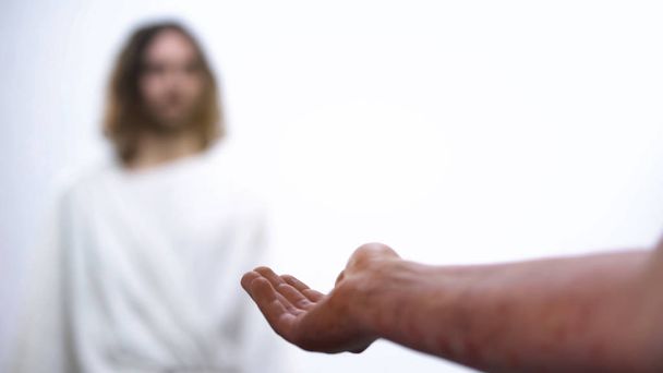Hand with rash holding out to God, ill person praying for health, healing - 写真・画像