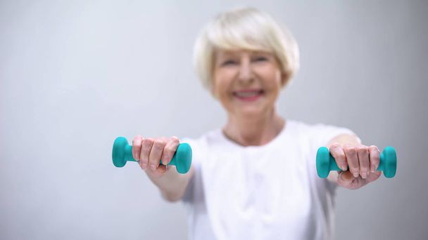 Active senior lady lifting dumbbell, exercises for health support, lifestyle - Foto, imagen