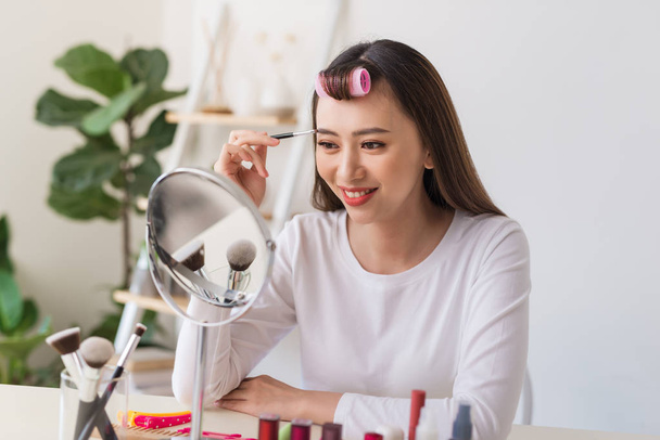 Attractive talented female blogger reviews beauty product for video blog, gives advice to girls and women, films process on camera. - Photo, Image