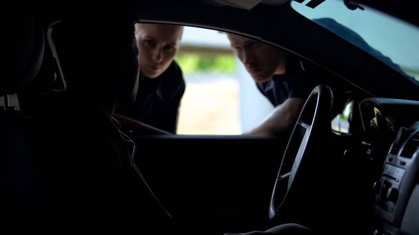 Polizeibeamte sprechen mit Fahrer im Auto, suchen gesuchten Verbrecher, überprüfen - Foto, Bild