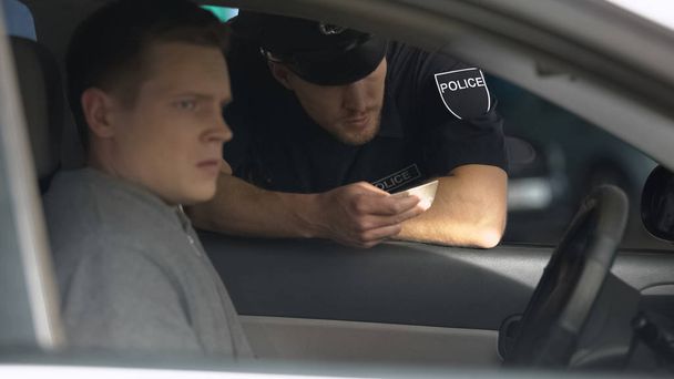 Police officer checking documents of nervous man in car, traffic control, rules - Fotografie, Obrázek