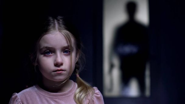 Φοβισμένο θηλυκό παιδί που κλαίει στη σκιά της κάμερας του τύραννου πατέρα με ζώνη έξω - Φωτογραφία, εικόνα