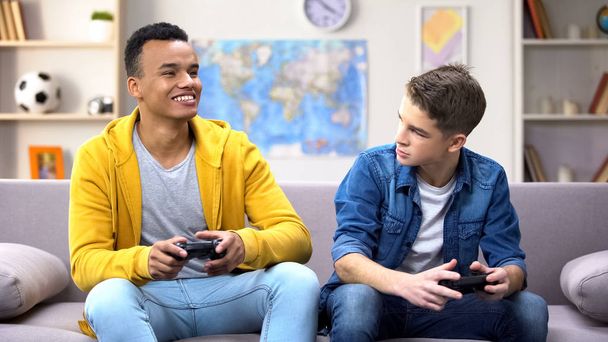 Emotional multiracial male teen friends playing video game, hobby and rivalry - Foto, imagen