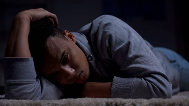Depressed african-american teenager suffering loneliness in dark room, abuse - Foto, immagini