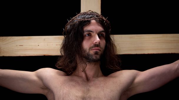 Jesus Christ in thorns crown on black background, religious faith, crucifix - Foto, imagen