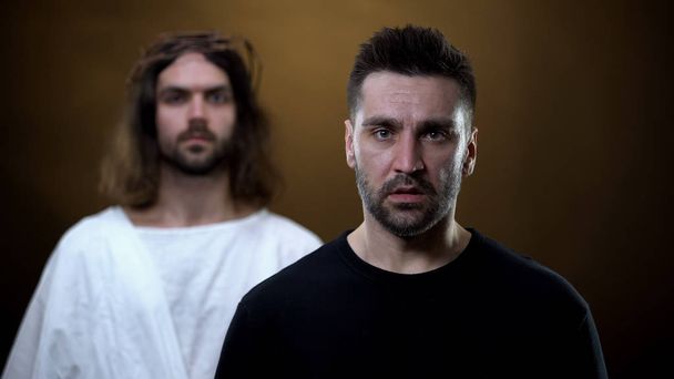 Sad man with messiah on background looking camera, spiritual support, faith - Φωτογραφία, εικόνα