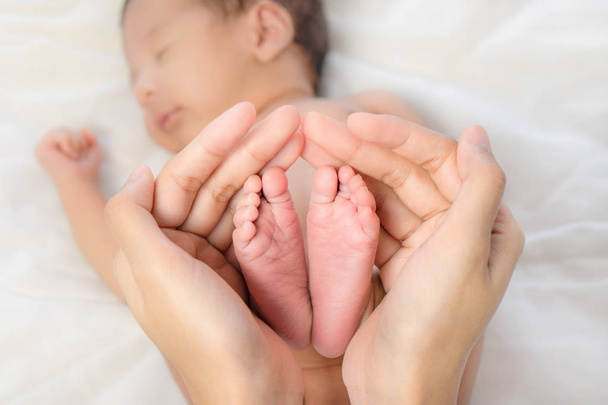 closeup of mother's hands holding baby boy feet - 写真・画像