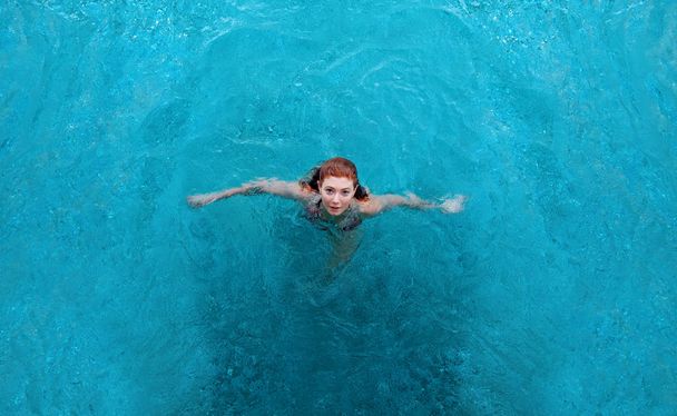 young sexy woman with red hair standing in bikini in the spa pool and looking up, copy space - Photo, Image