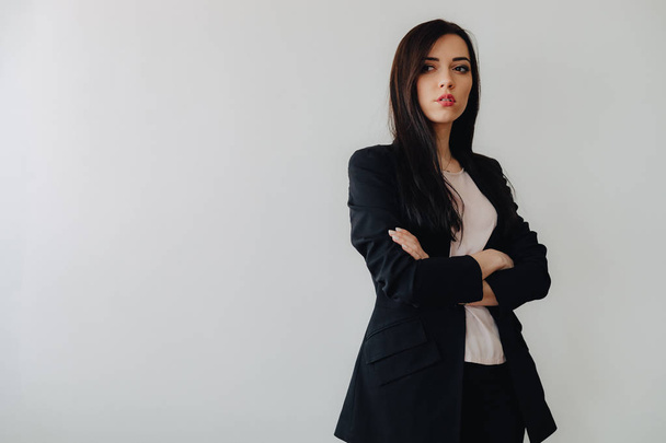 Young attractive emotional girl in business-style clothes on a plain white background in an office or audience - Foto, afbeelding