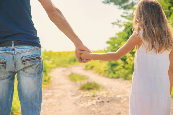 Père et fille marchent en se tenant la main. Concentration sélective
. - Photo, image