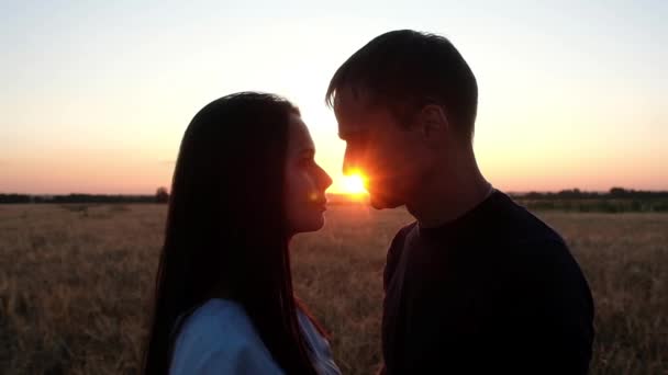 a young couple kissing on the background of a summer sunset. Silhouette of a man and a woman in the sun. Romantic relationship in nature. love traditional. - Footage, Video