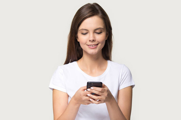 Lächelndes Millennial-Mädchen mit modernem Smartphone im Internet surfen - Foto, Bild