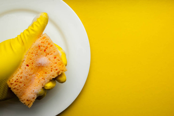 Spugna di pulizia su un piatto bianco su sfondo giallo
 - Foto, immagini