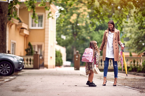 Cute little girl with backpacks going to school with her mother - Foto, imagen