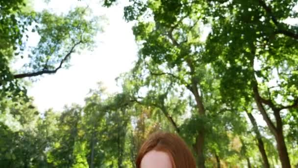 Chica utiliza su teléfono inteligente en el parque en un banco de madera
 - Metraje, vídeo