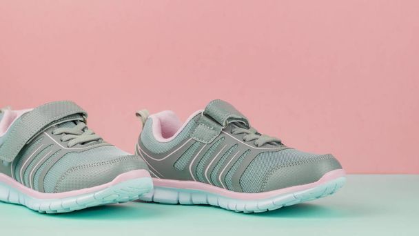 Pair of fashionable sports shoes on pink and blue background. - Photo, Image