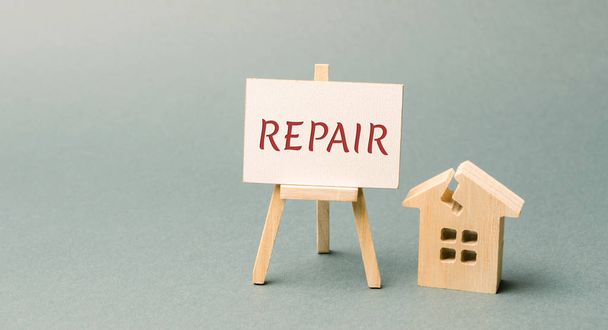 Ruined house and a poster with the word Repair. The concept of a damaged house, dilapidated housing. Home repair after disaster. Renovation, restoration of the old building. Property insurance. Damage - Φωτογραφία, εικόνα