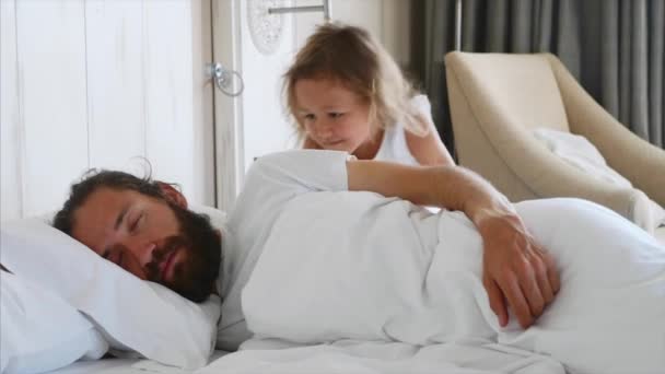 Little daughter comes to sleeping father, wakes him and lies down beside him - Imágenes, Vídeo