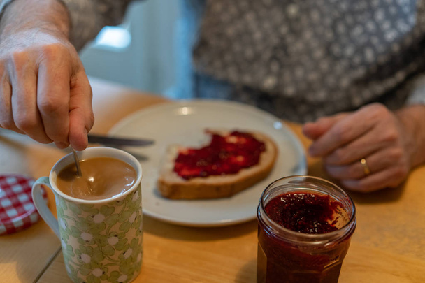 A man stir the coffee eating swiss breakfast - Foto, Bild