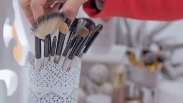 A make up artist takes out a fan brush and then she puts it back on its place. - Footage, Video