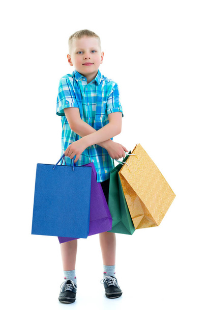 Little boy waving multicolored paper bags. He goes shopping - 写真・画像