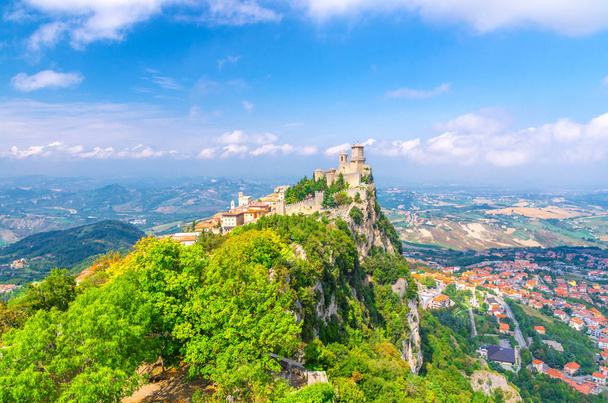 Republic San Marino Prima Torre Guaita first fortress tower with brick walls on Mount Titano stone rock with green trees, aerial top panoramic view of landscape valley and hills of suburban district - Photo, Image