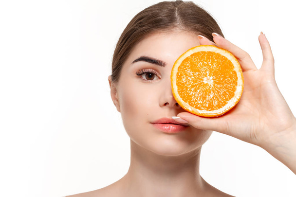 Close-up retrato de uma bela menina feliz segurando metade das laranjas perto do rosto isolado sobre fundo branco
. - Foto, Imagem