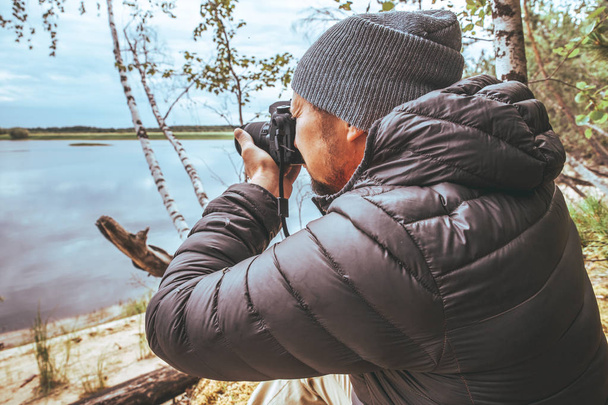 ein Mann in grauer Jacke fotografiert die Natur am Ufer des Flusses, im Wald - Foto, Bild