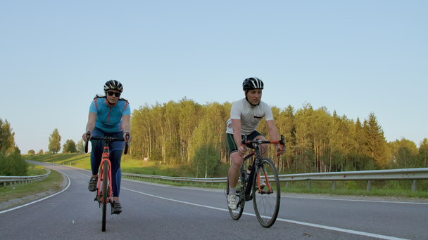 Na kopci jezdí dva profesionální cyklisté na kole. V teplém, ale větrném letním dni se střídalo u dvou silných cyklistů a samců.. - Záběry, video