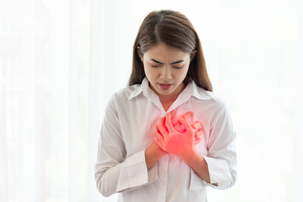 Mujer asiática teniendo un ataque al corazón mientras las manos tocan su pecho
,  - Foto, imagen