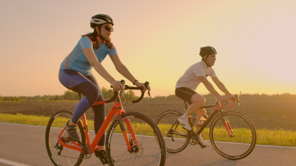 Kaksi pyöräilijää ratsastaa yhdessä vuorilla. Pehmeästi keskittynyt kädessä pidettävä kuva kahdesta ammattilaispyöräilijästä urheilujoukkueesta, joilla on hauskaa kovan harjoittelun aikana, sprinting
. - Materiaali, video
