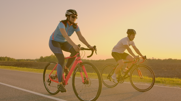 Espaço Vazio. Amigos desportivos de bicicleta ao pôr-do-sol. Dois ciclistas vão ao longo da costa. Desporto no fundo da natureza. Grupo de pessoas dois motociclista de estrada no por do sol
 - Filmagem, Vídeo