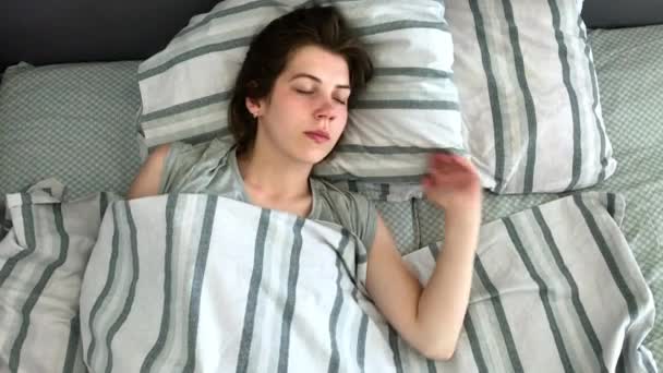 Piękna młoda brunetka charmingly śpi w łóżku we wczesnych godzinach porannych. Słodki i ciepły widok z dziewczyna Sleeping Calmly - Materiał filmowy, wideo