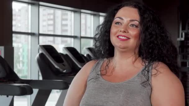 Ευτυχισμένο συν μέγεθος αθλητική γυναίκα ανύψωση βαράκια στο γυμναστήριο - Πλάνα, βίντεο
