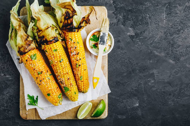 Roasted or grilled sweet corn cobs with garlic butter and lime.  - Foto, afbeelding