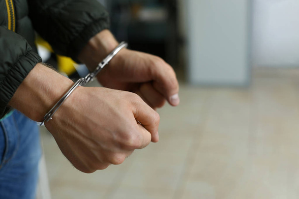 Man detained in handcuffs indoors, space for text. Criminal law - Фото, зображення