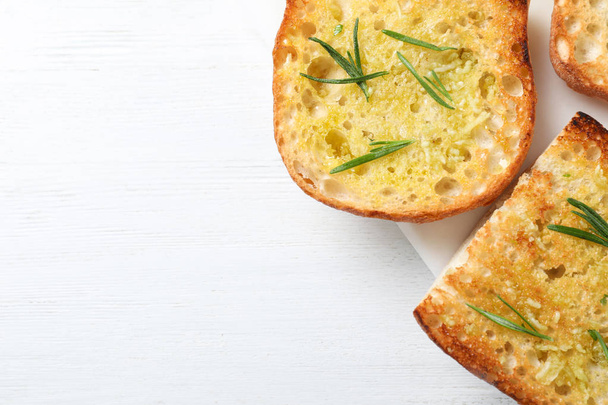 Slices of toasted bread with garlic and herb on white wooden table, top view. Space for text - Foto, Imagen