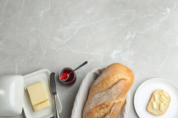 Tasty fresh bread with butter and jam on light marble table, flat lay. Space for text - Fotoğraf, Görsel