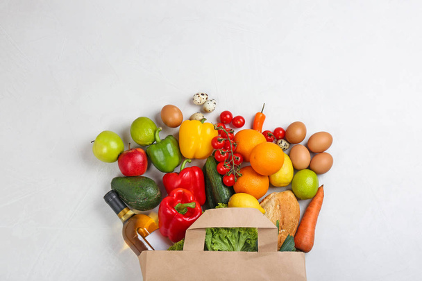 Flat lay composition with overturned paper bag and groceries on white table - Foto, Imagen