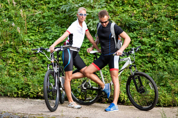Hombre y mujer en bicicleta en ropa deportiva. En el parque
. - Foto, imagen
