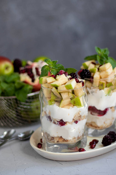 Curd dessert. Made from apples, pears, cookies, decorated with mint and blackberry. Diet. Near apples, pears, pomegranates, grapes, lime. Near glasses of raspberries. Healthy eating Light breakfast.  - Foto, Bild