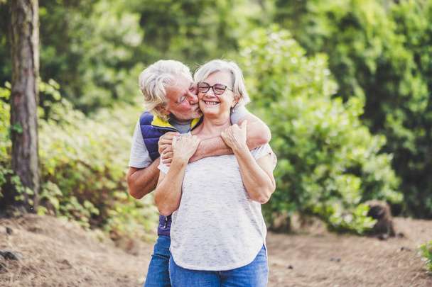 casal de caucasianos idosos ativos beijando em relação com plantas verdes natureza em segundo plano
  - Foto, Imagem