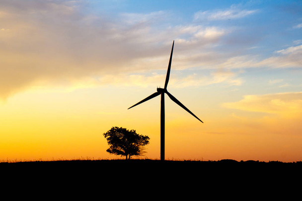 Tuulivoimapuiston siluetti laskevan auringon taustalla
 - Valokuva, kuva