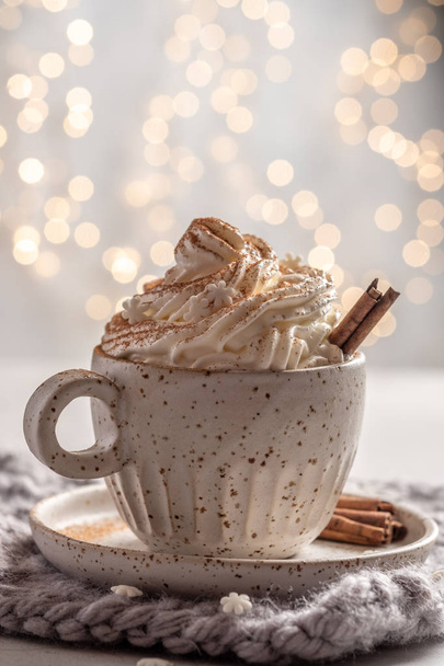 Hot chocolate with cream and cinnamon stick in a ceramic cup - Foto, afbeelding