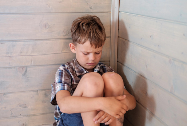ображений сумний хлопчик сидить на підлозі в кутку кімнати
 - Фото, зображення